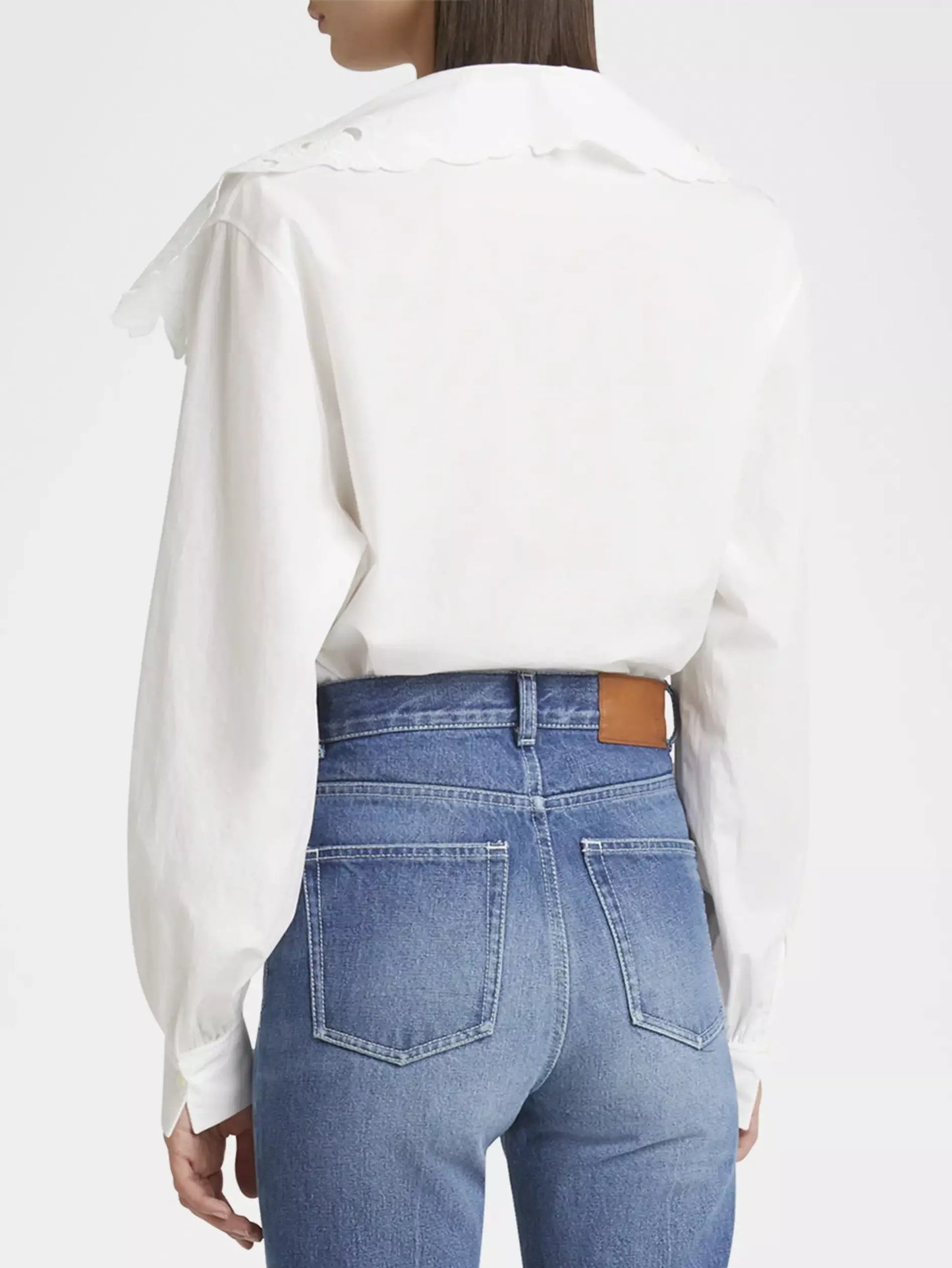 Woman in a white broderie anglaise cotton poplin blouse and blue jeans