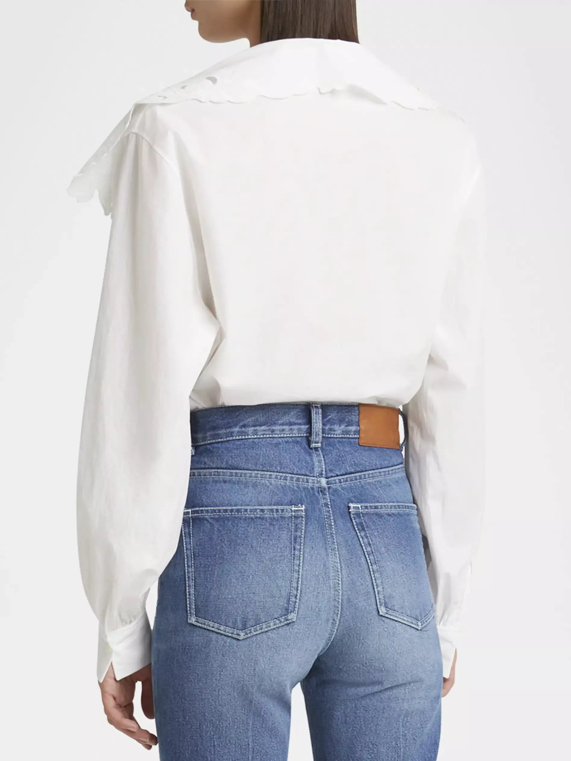 Woman in a white broderie anglaise cotton poplin blouse and blue jeans