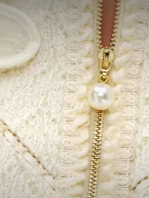 Cream-colored knit cardigan featuring pearl zipper pull for the embroidered tweed zip-front jacket