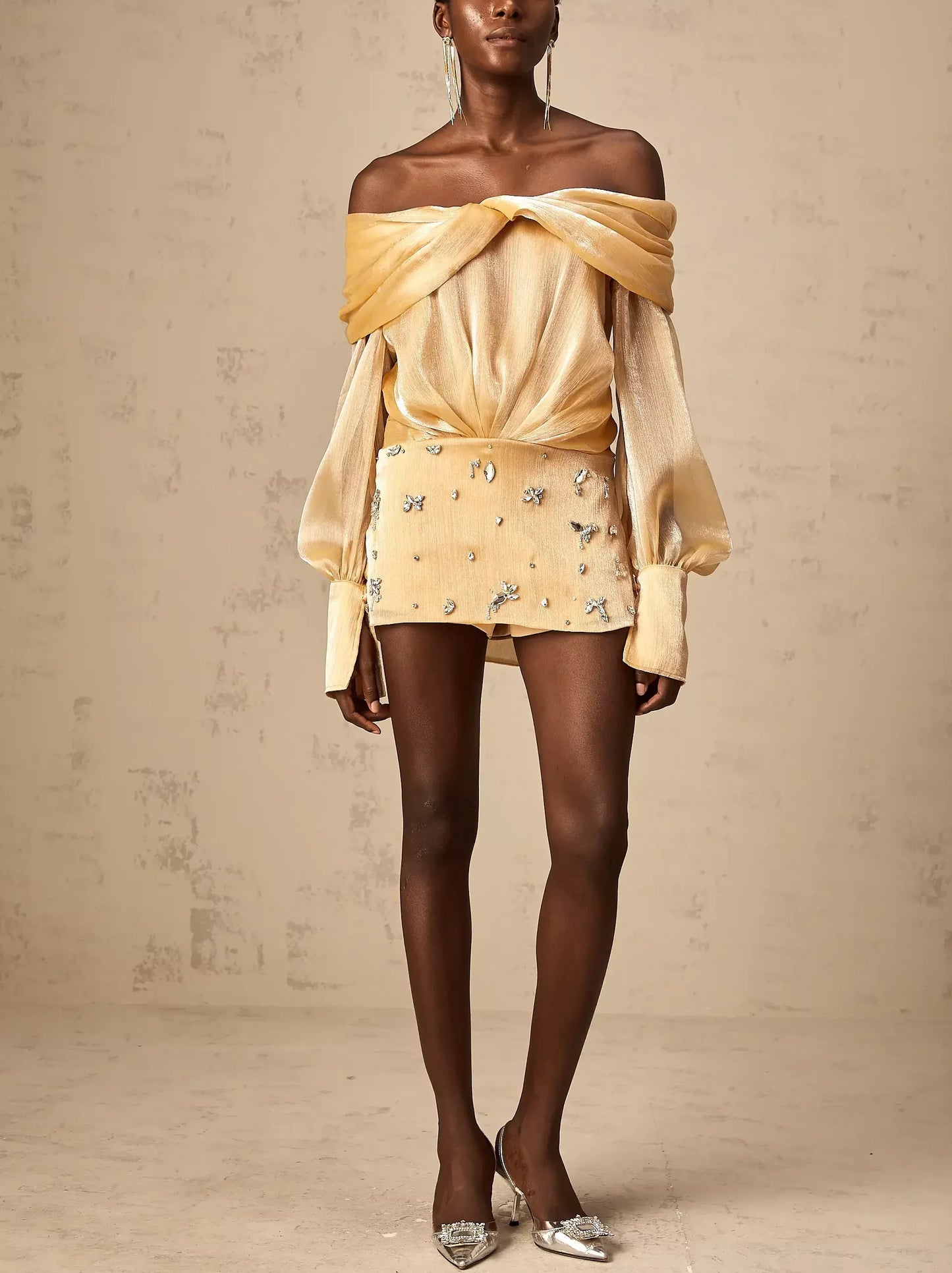 Woman in a luxurious satin gold off-shoulder mini dress with rhinestone embellishments