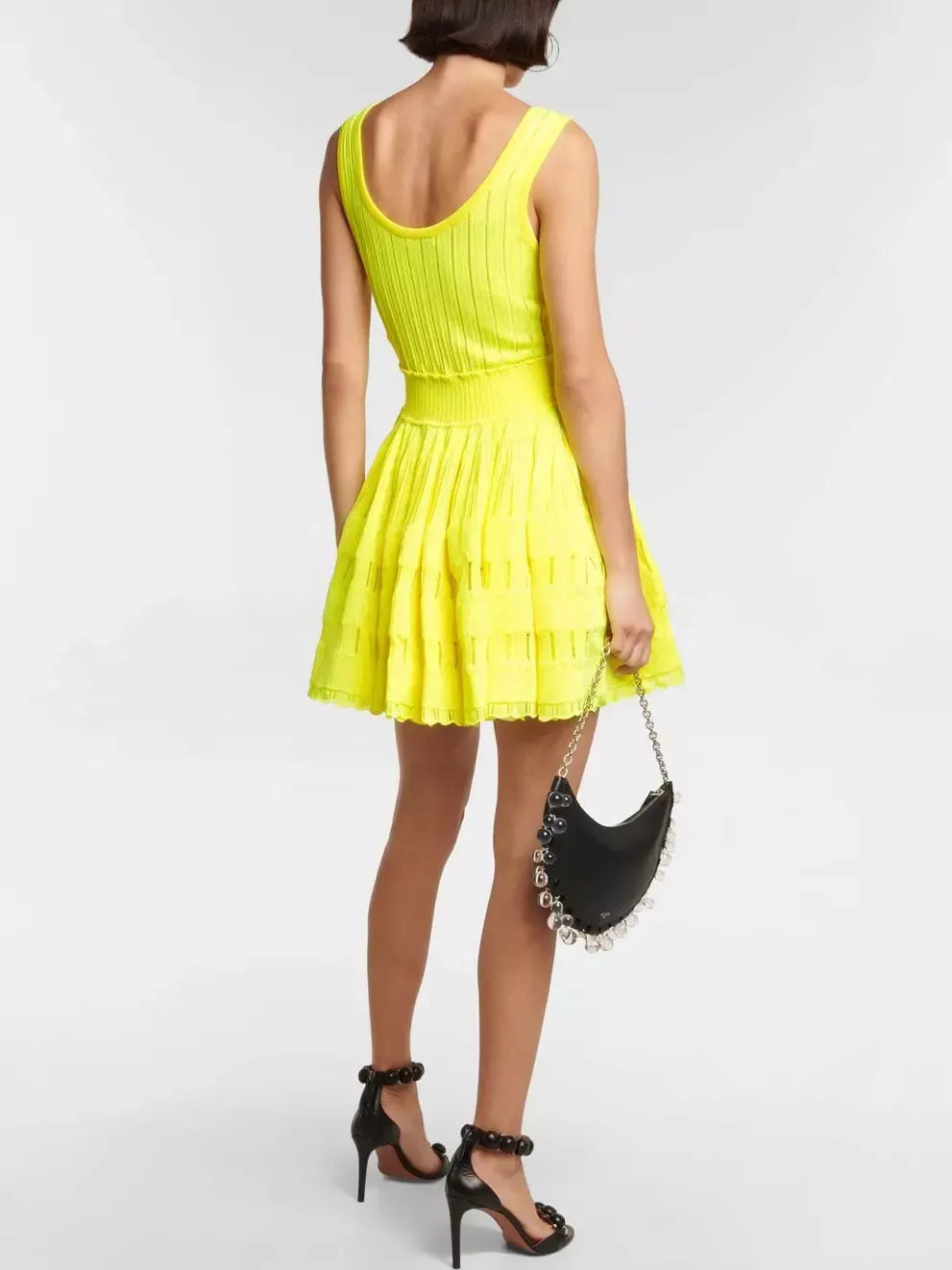 Woman in a bright yellow flare skater tank dress with black heels and purse