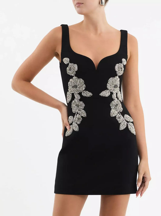 Bead-embellished black sleeveless mini dress with floral embellishments on model