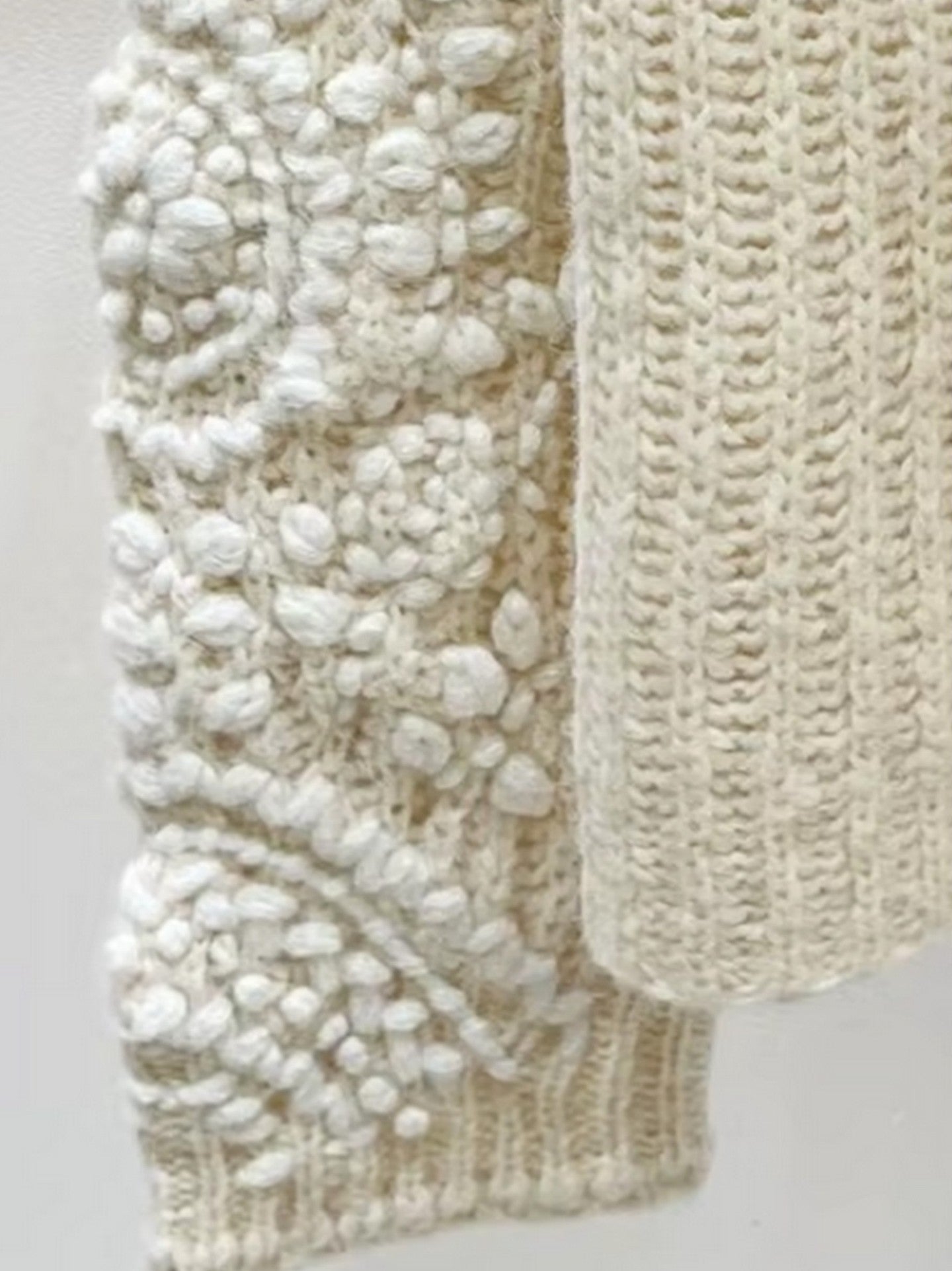 Cream-colored chunky embroidered knit turtleneck sweater with textured sleeves