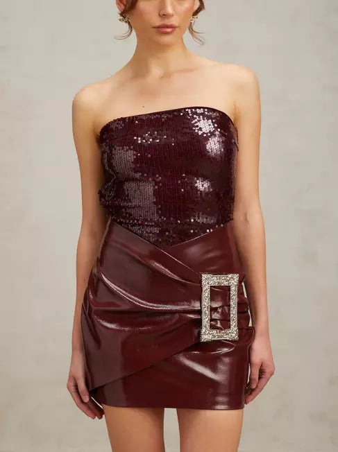 Burgundy strapless sequin mini dress with buckled wrap effect and faux leather skirt