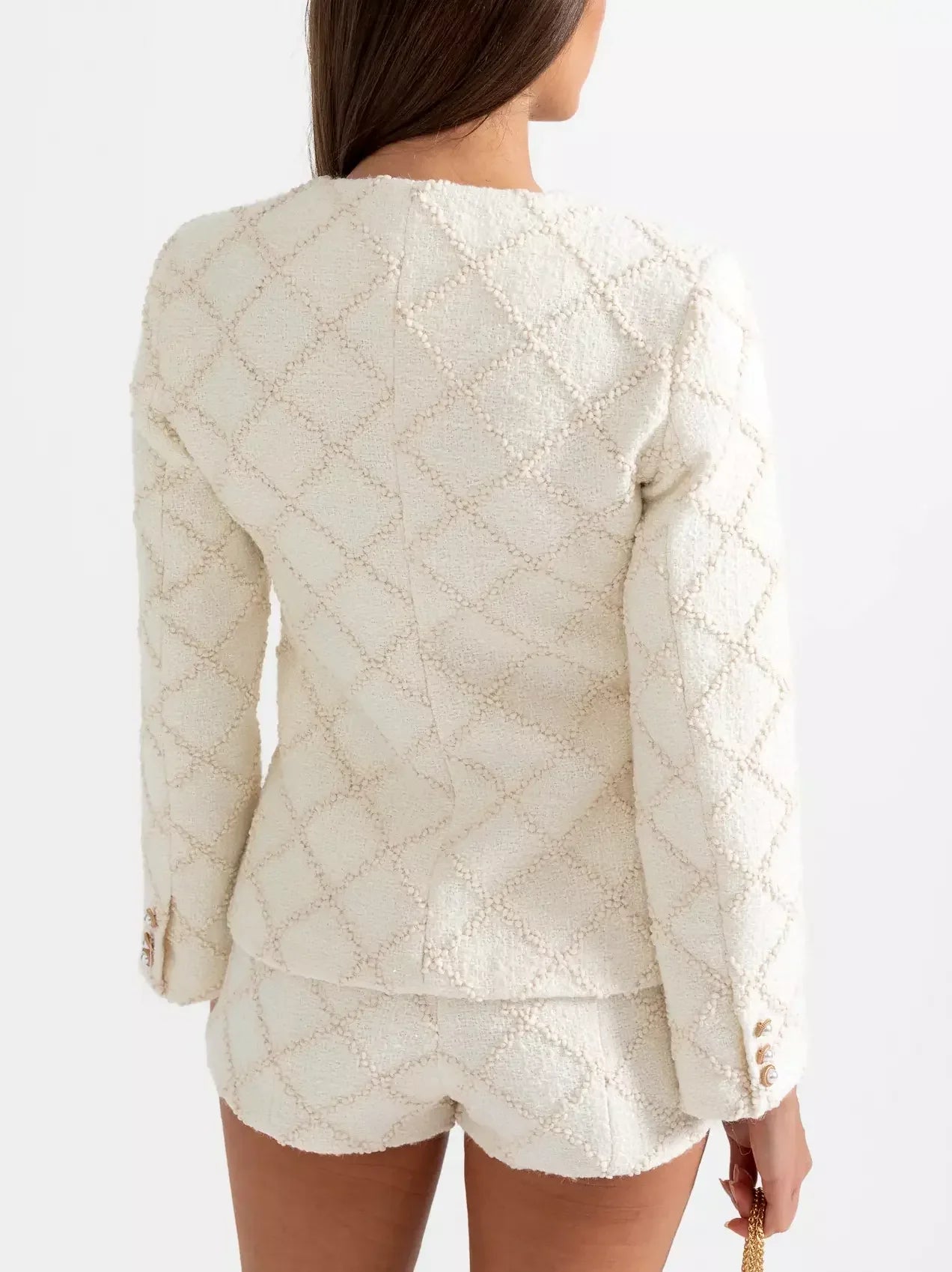 Cream-colored textured tweed jacket and matching short set displayed elegantly